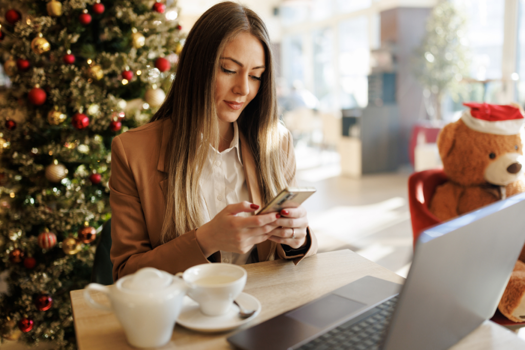 woman messaging on phone around holiday decor